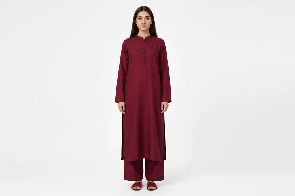 A woman modeling a long-sleeved maroon kurta and matching palazzo pants set against a plain white studio background.