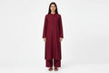A woman modeling a long-sleeved maroon kurta and matching palazzo pants set against a plain white studio background.