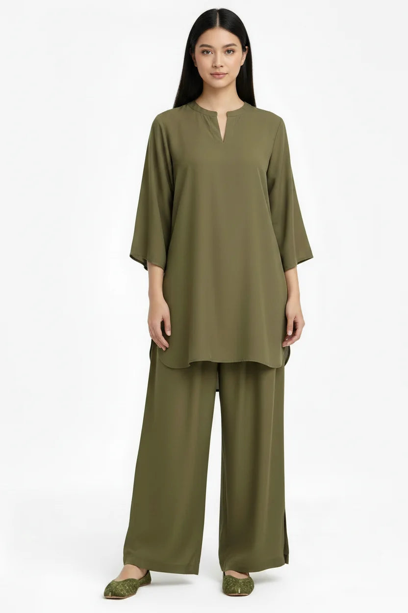 A woman modeling a matching olive green two-piece lounge set consisting of a short-sleeve tunic top with a split neckline and wide-leg pants, photographed against a plain white studio background.