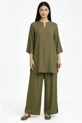 A woman modeling a matching olive green two-piece lounge set consisting of a short-sleeve tunic top with a split neckline and wide-leg pants, photographed against a plain white studio background.