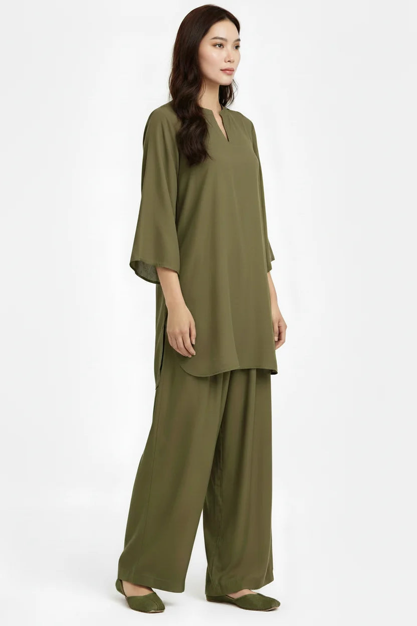 A woman modeling a matching olive green two-piece lounge set consisting of a short-sleeve tunic top with a split neckline and wide-leg pants, photographed against a plain white studio background.