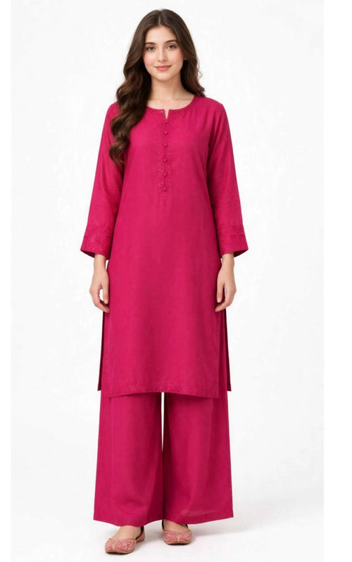 A woman modeling a bright magenta pink kurta set with matching wide-leg pants, featuring a three-quarter sleeve design and a buttoned neckline, set against a plain white background.